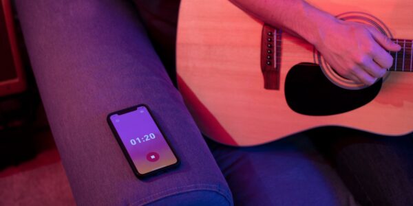 Guitarist recording acoustic performance with smartphone