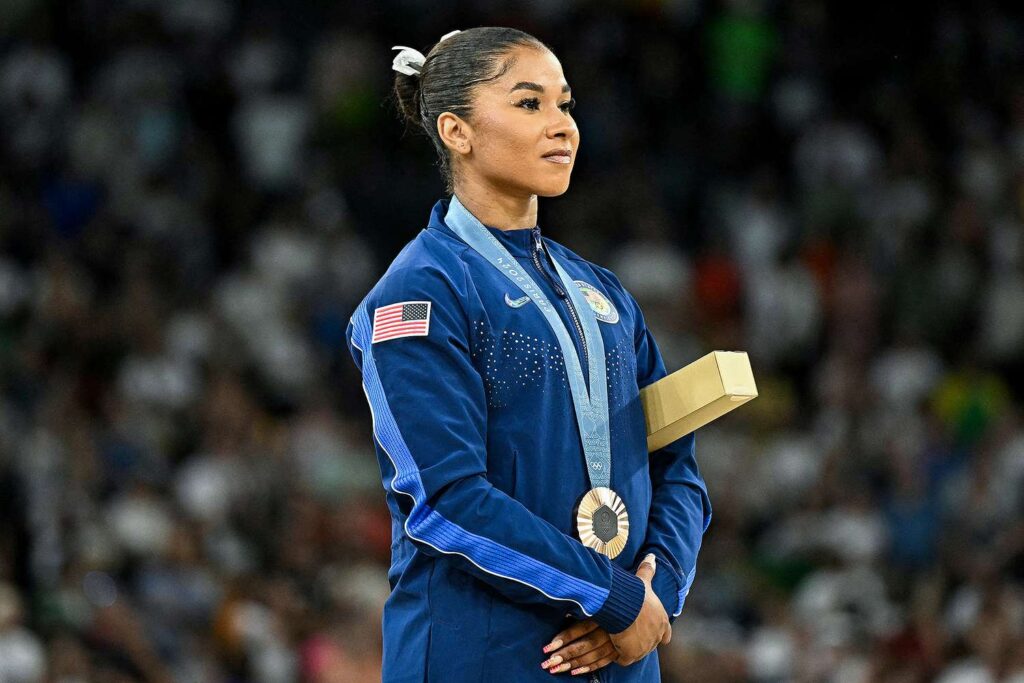 Jordan Chiles wearing Team USA jacket on Olympic podium holding bronze medal